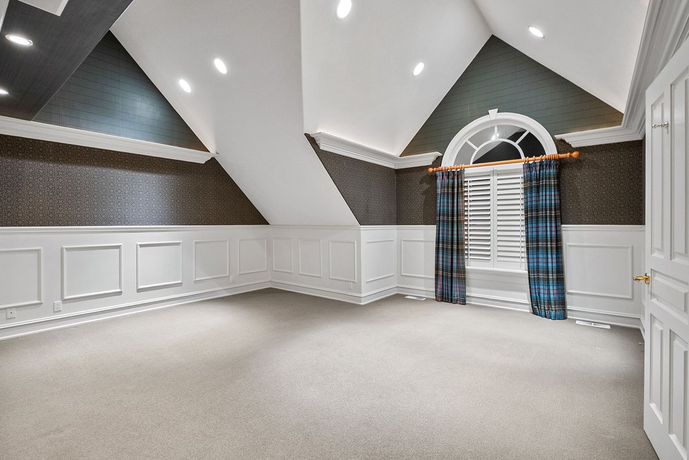 Spacious Guest Bedroom with Vaulted Ceilings, Wainscoting, and Dormer Window