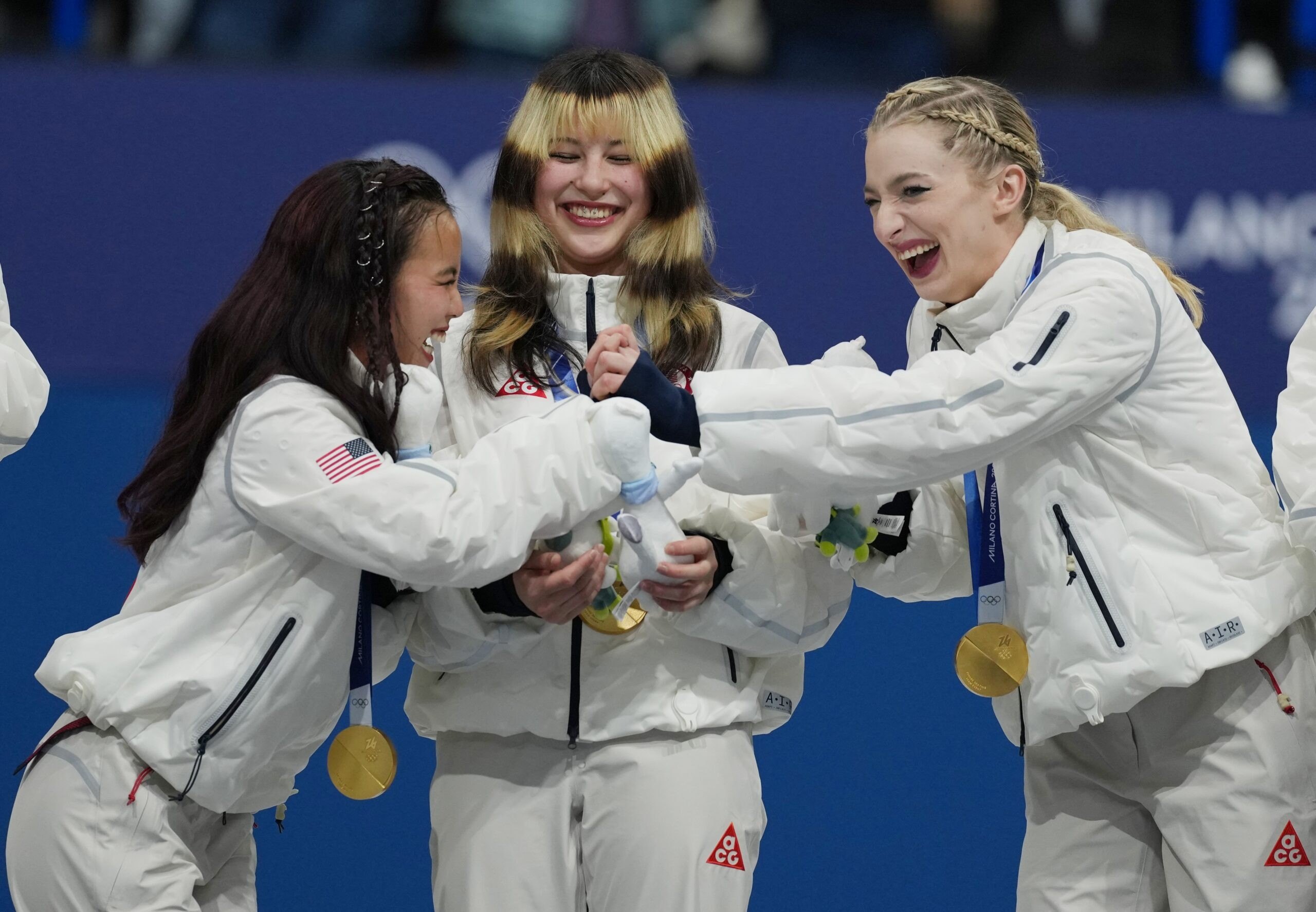 Gold medalists Ellie Kam Amber Glenn and Alysa Liu of team the United States react on the podium with gold medals