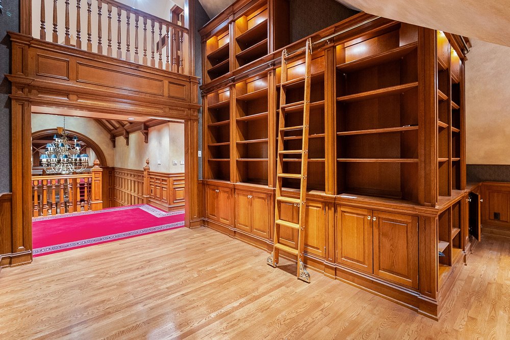 Upper Level Library Hallway with Floor-to-Ceiling Wooden Bookcases and Rolling Ladder