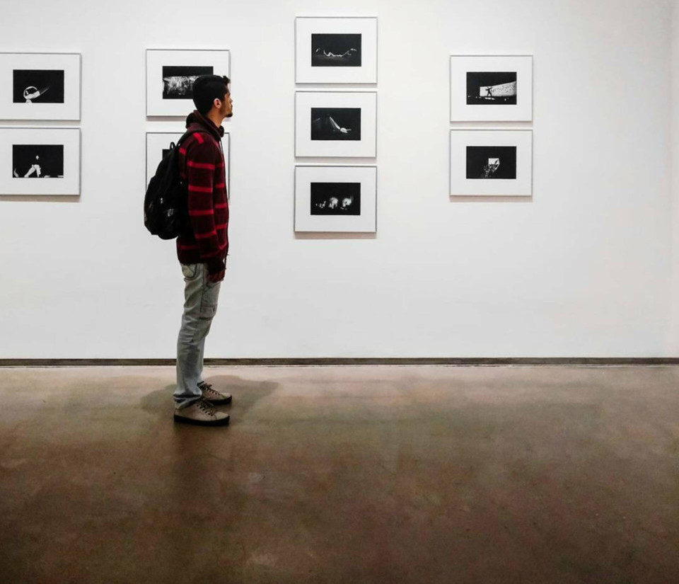 Man standing beside a gallery wall