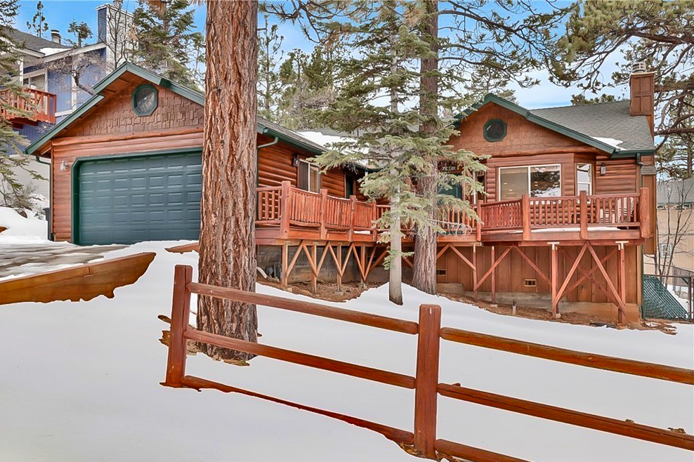 home in a snowy area with trees and an outdoor deck