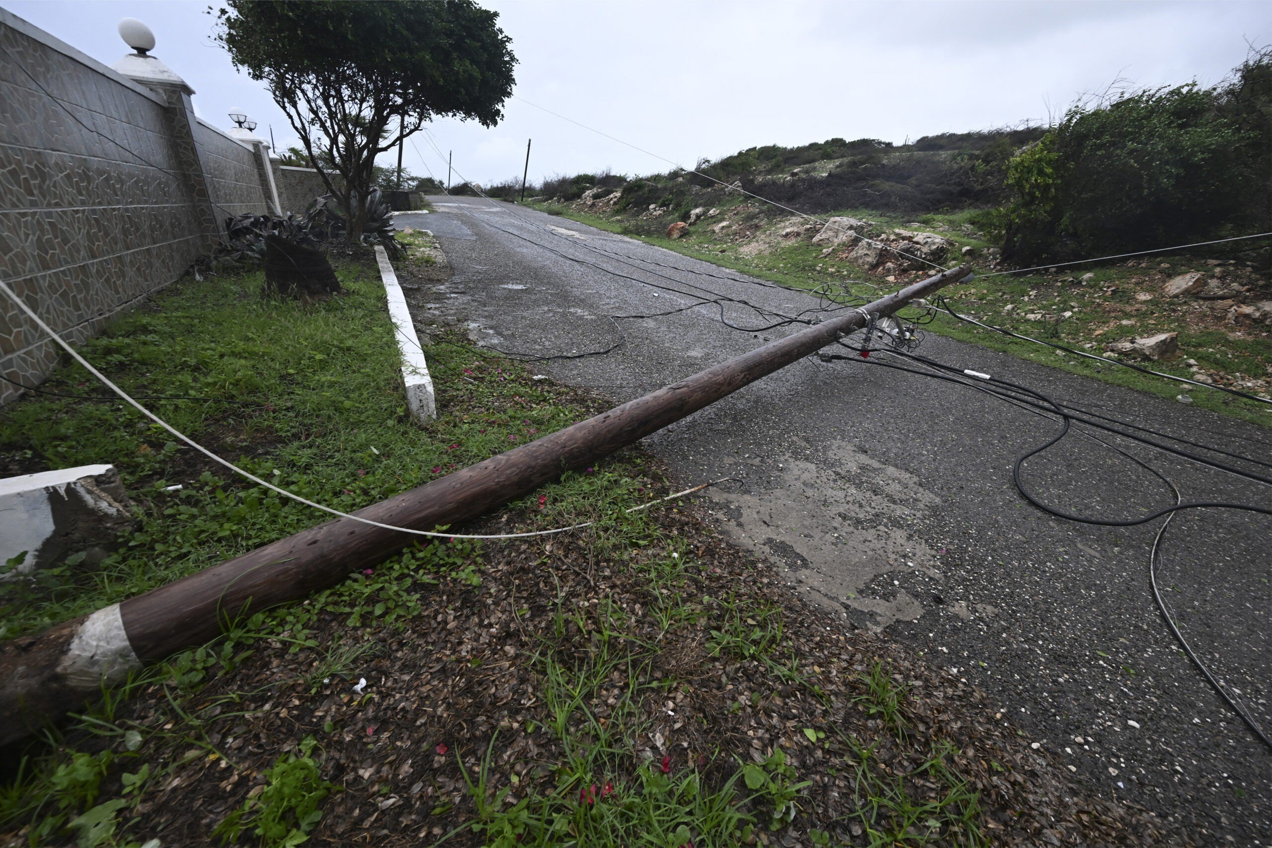 A fallen Jamaica Public Service Company light pole is seen on the Sugar Man's beach main road in Hellshire, St Catherine parish, near Portmore, as Jamaica starts to feel the effects of Hurricane Mellisa