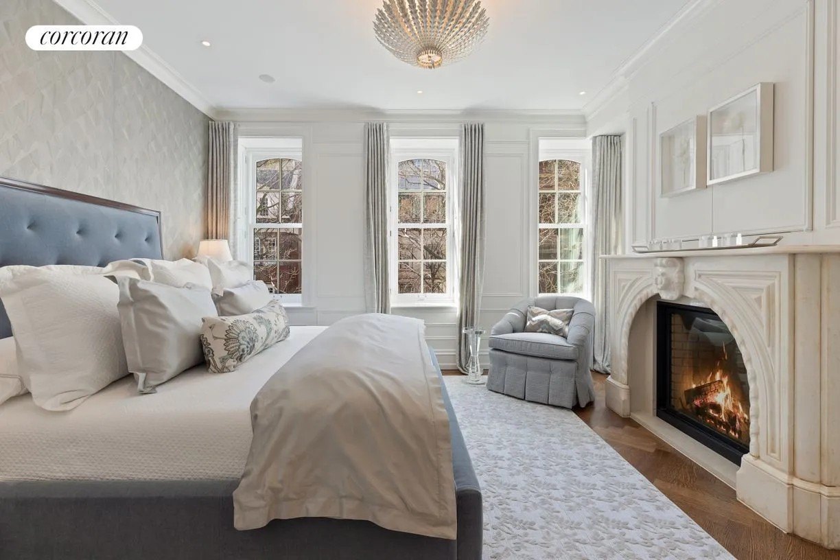 A bedroom with a fireplace in the ‘Breakfast at Tiffany’s’ Townhome after a gut renovation