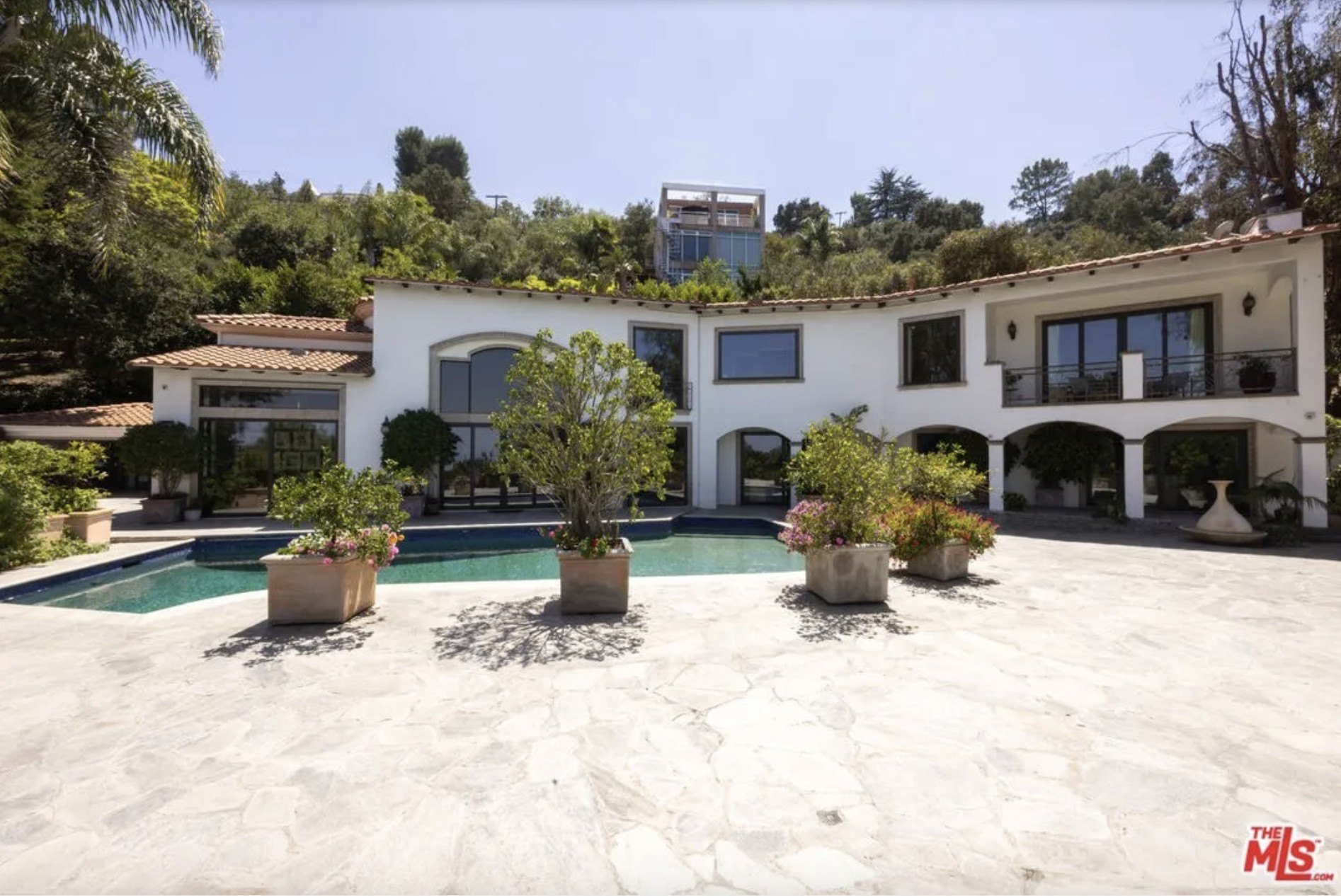 A mansion with a pool out front and palm trees in L.A.