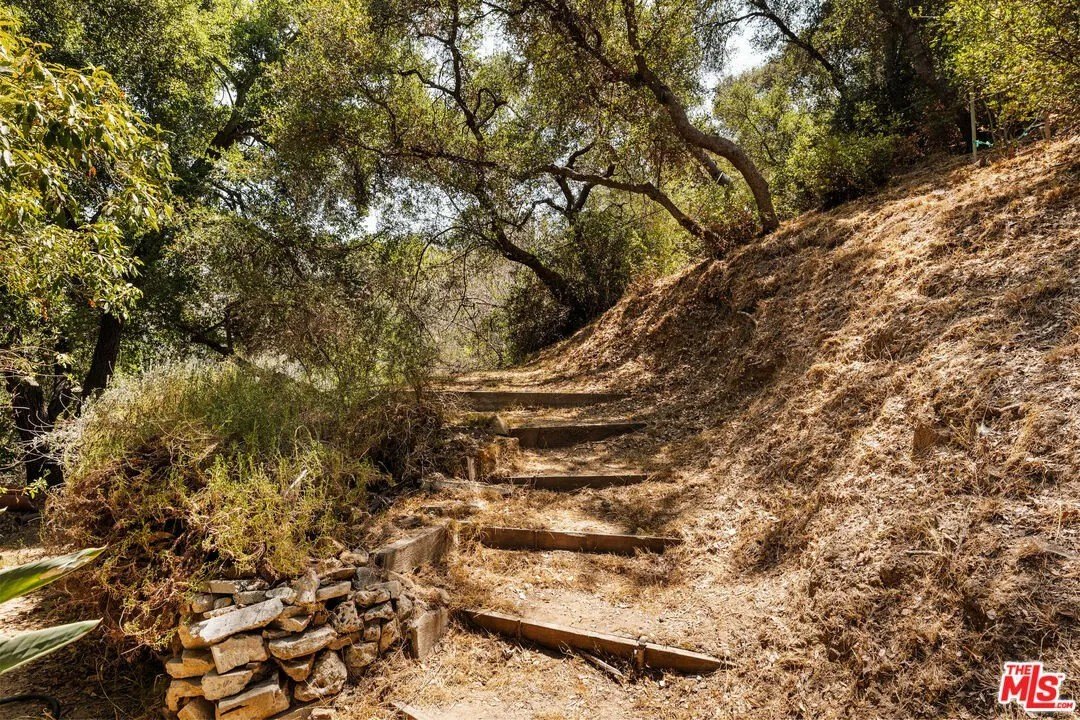 The expansive lot, which measures over half an acre, features canyon views and shaded hiking trails.