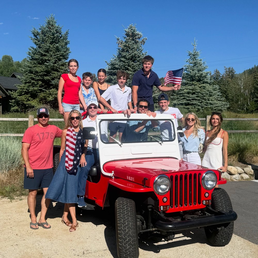 Large Family Group Posing on a Vintage Red Jeep Out-of-Doors