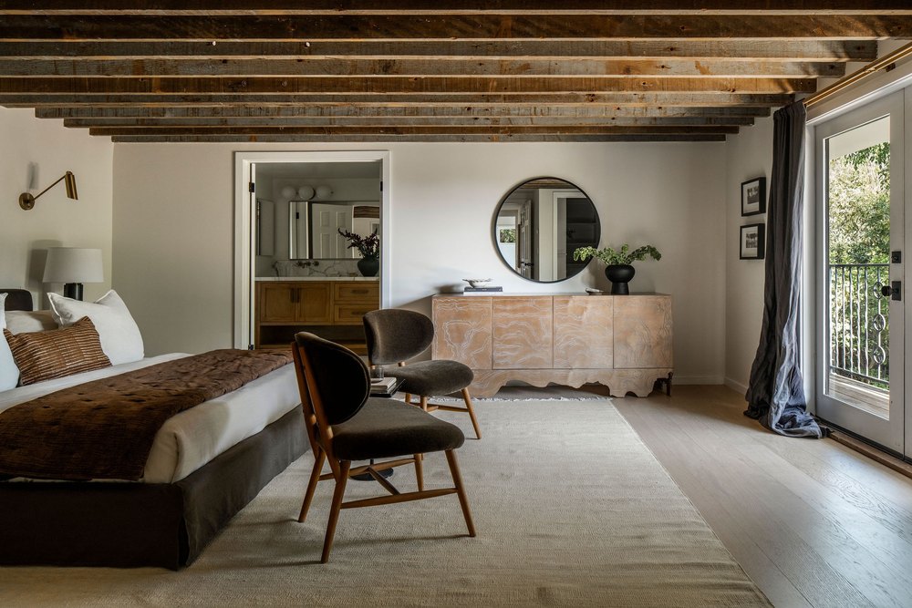 A bedroom with wooden beams on the ceiling and a connecting bathroom in actress Malin Akerman home in Los Feliz California