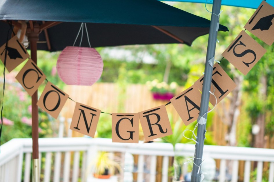a banner reading "congrats" hangs outside on the porch at a home graduation party