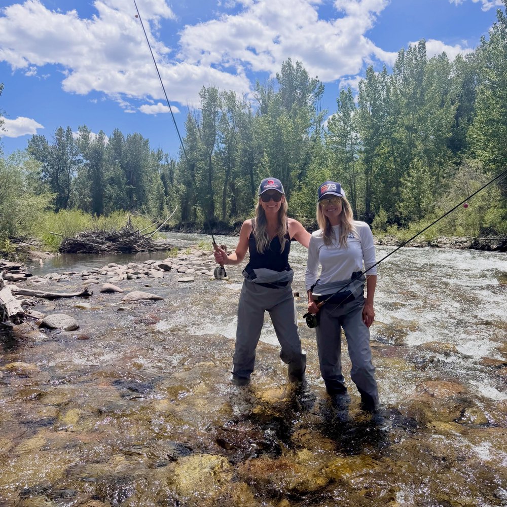 Two Women Holding Fishing Rods While Fly Fishing in a River