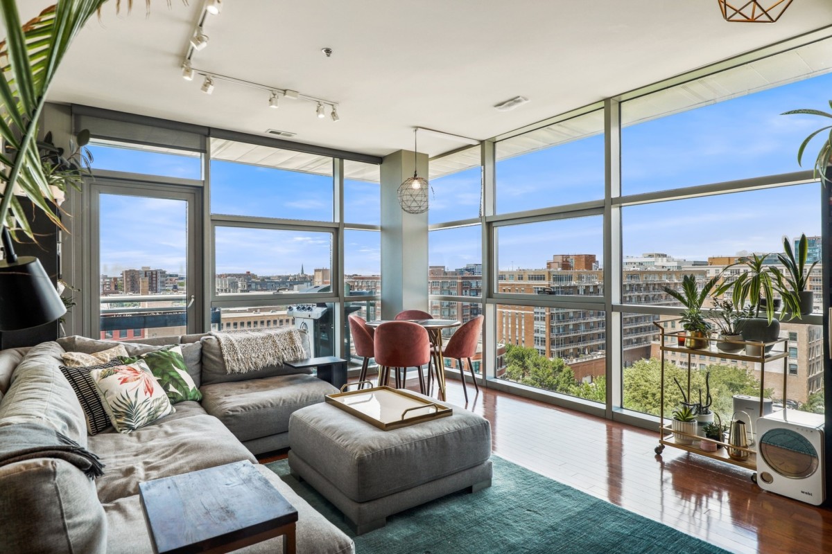 apartment with floor to ceiling windows and exposed pipes