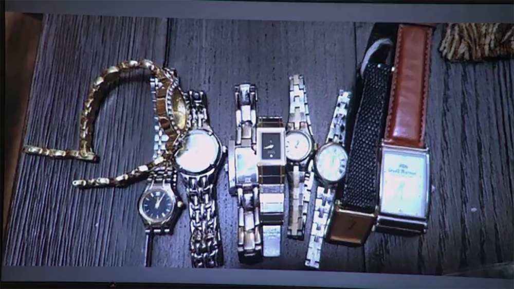 Multiple recovered luxury wristwatches with gold, silver, and leather straps arranged on a wood table.