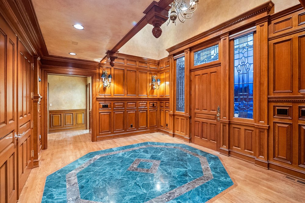 Ornate Wood-Paneled Foyer with Blue Geometric Tile Inlay Floor