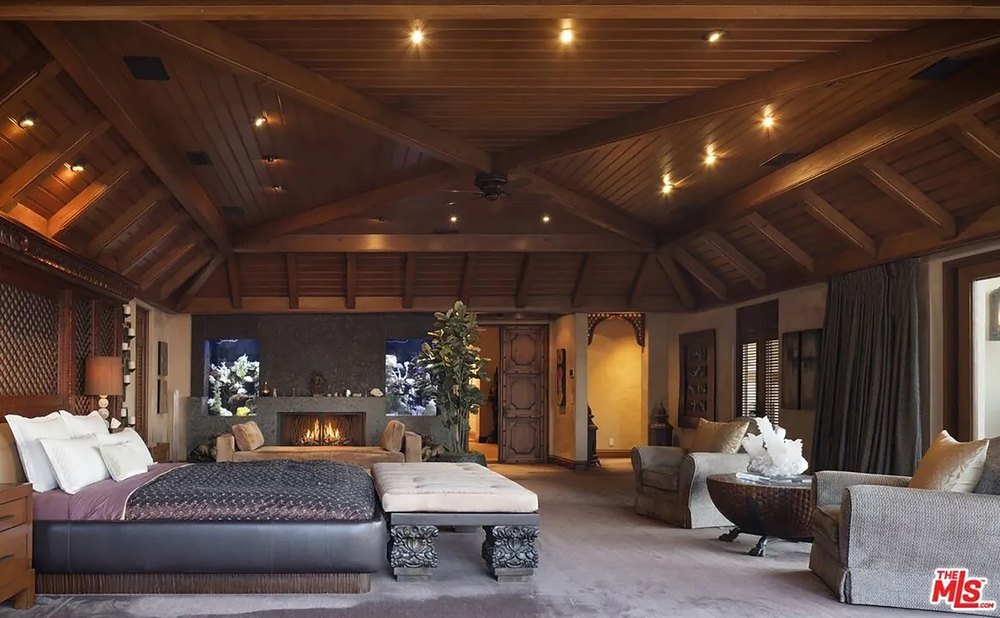 Primary bedroom suite with an integrated sitting area, a linear fireplace, and sophisticated wood paneling.