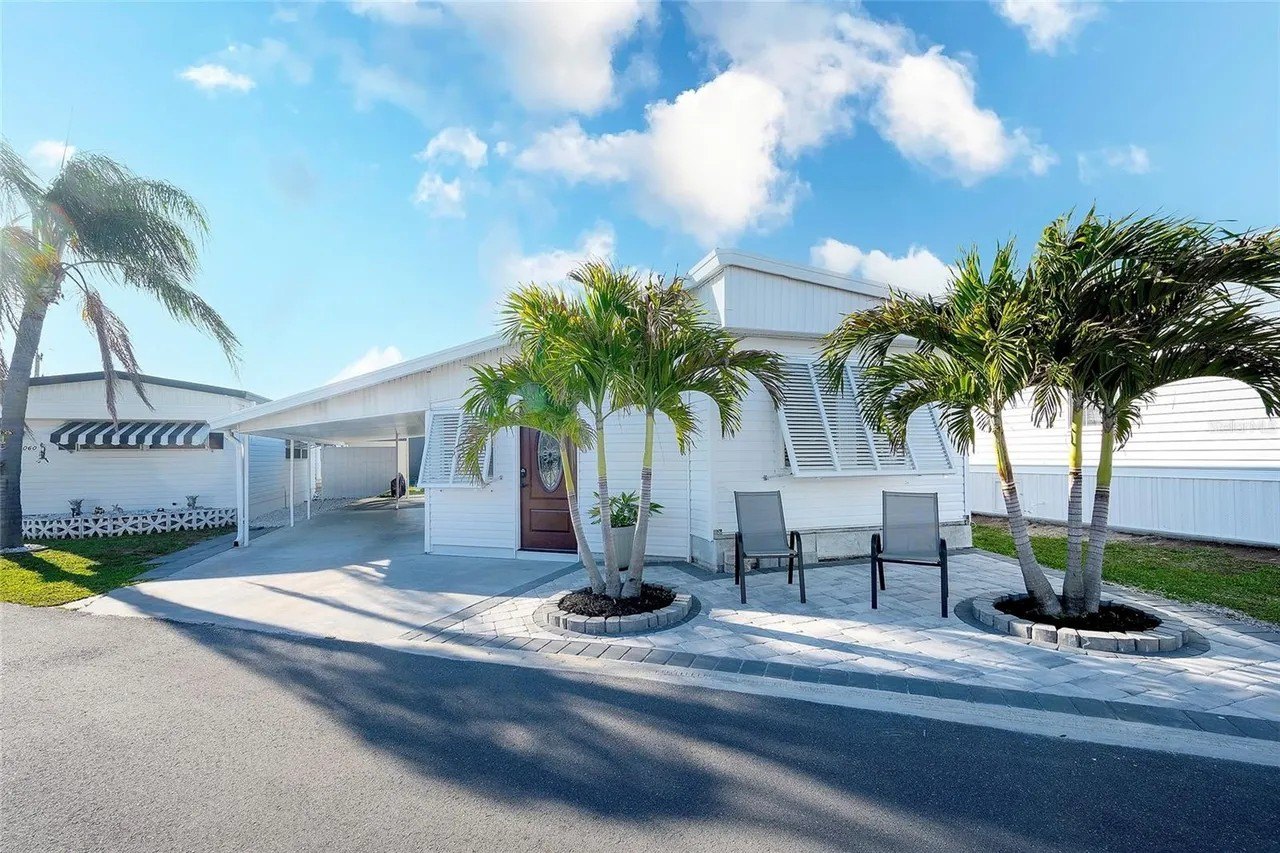 White mobile home with palm trees in front