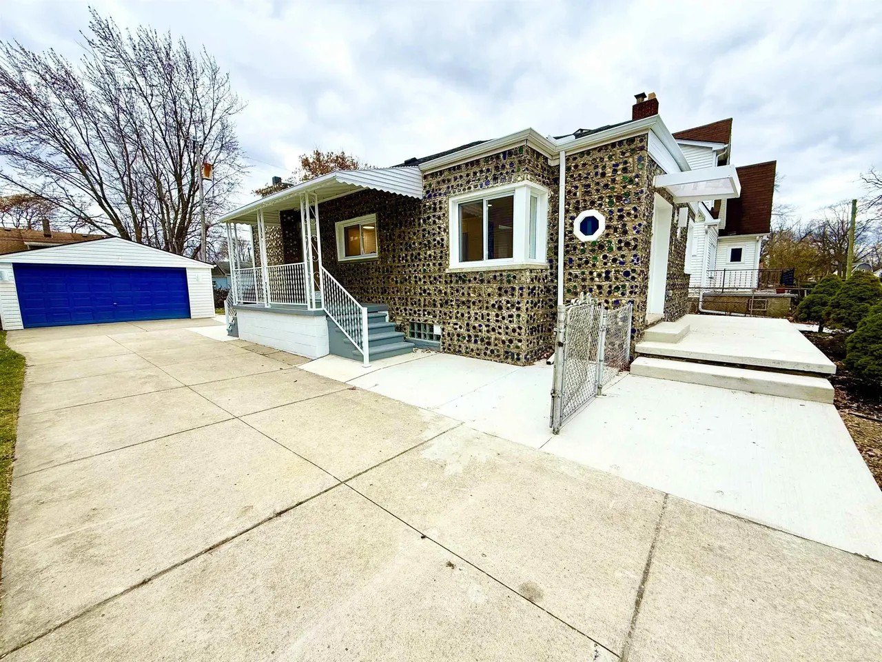 A two-car garage was added along the way. Schiller painted the door "Noxema Blue" to match the blue glass bottles in the exterior walls.