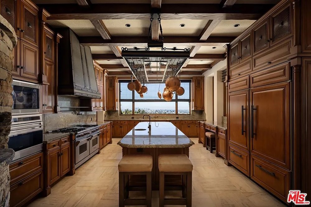 Gourmet chef's kitchen featuring high-end wood cabinetry, a large center island, and hanging copper cookware.