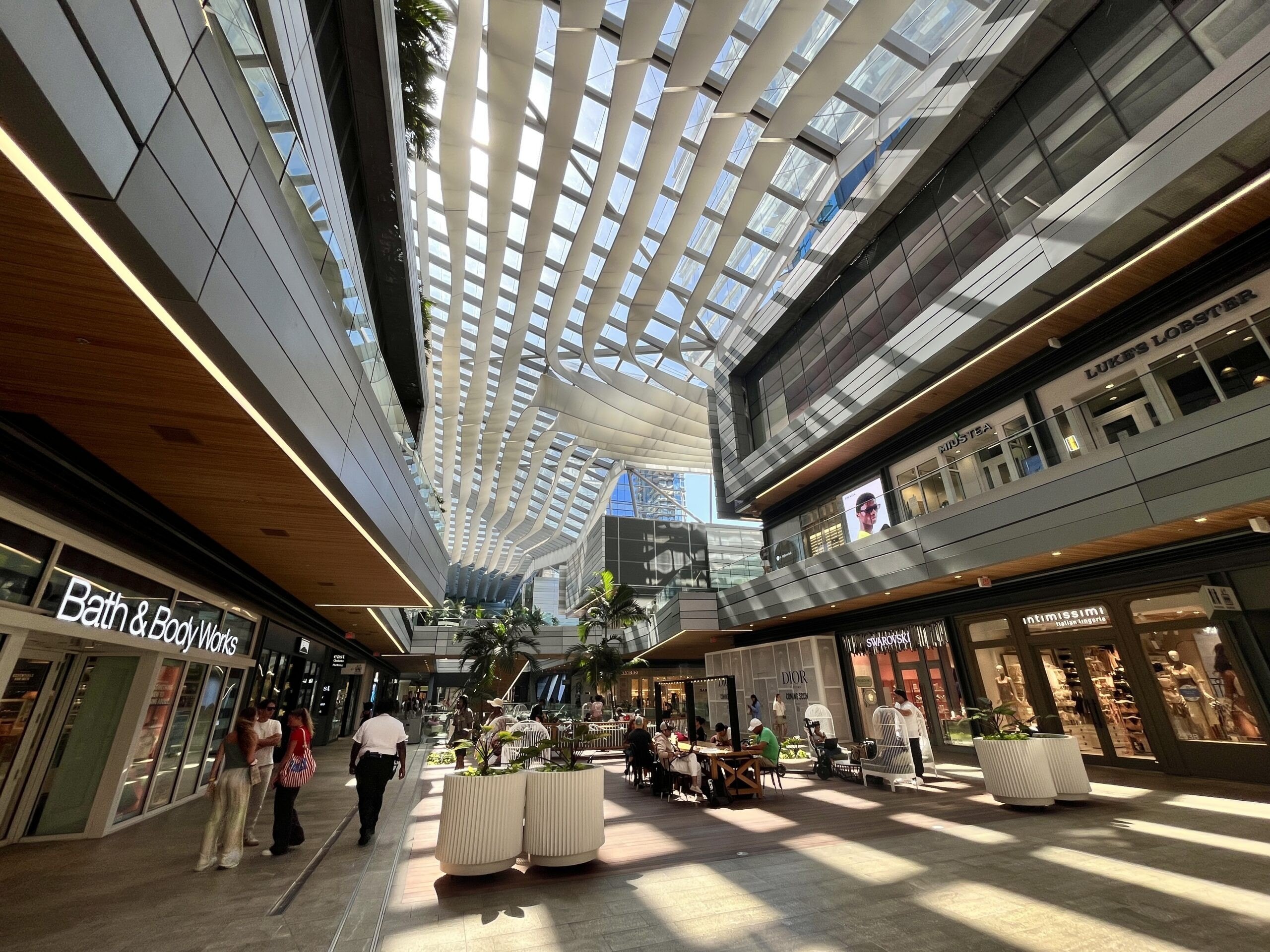 People enjoying a sunny day shopping and dining at the luxurious open-air mall, Brickell City Centre, with its iconic climate ribbon architectural design