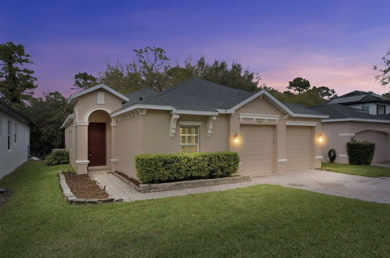 A foreclosed home in Oviedo, FL, with a yard and shrubs is seen at dusk