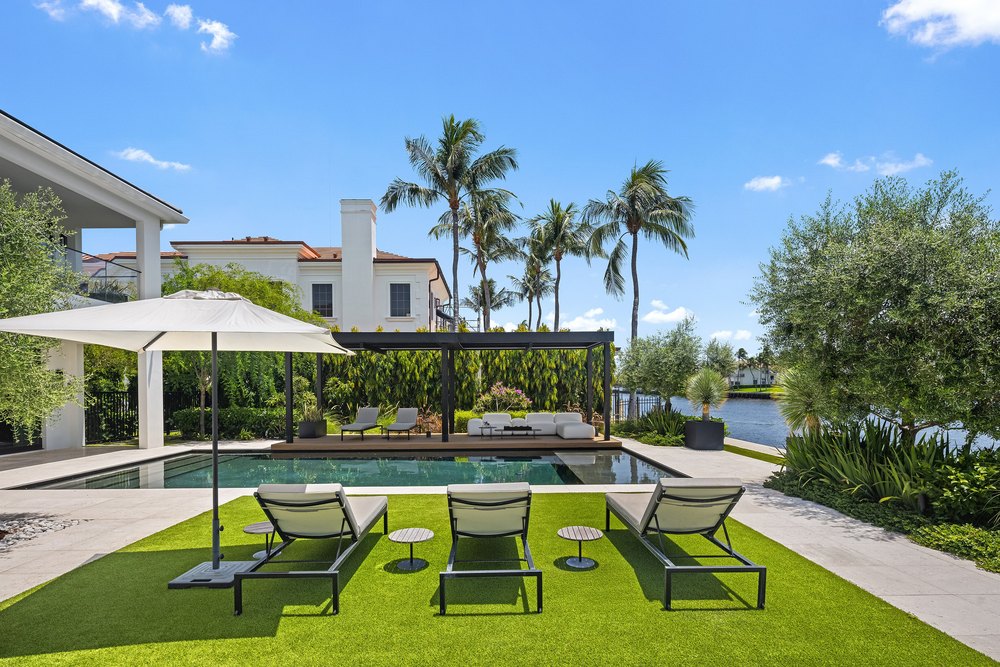 Luxury Swimming Pool Deck with Sun Lououngers, Lawn Area, and Palm Trees
