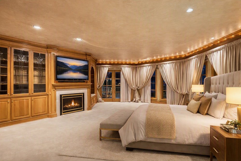 Staged Primary Bedroom Suite with Fireplace, Built-In Cabinetry, and Drape Curtains