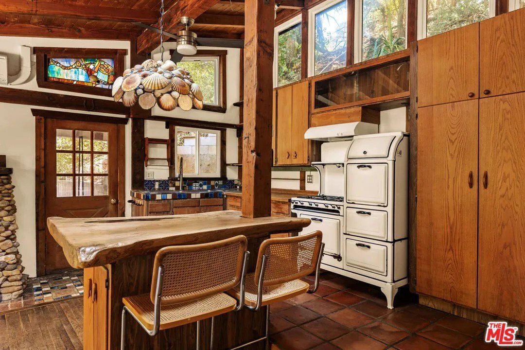 The kitchen features a a working, vintage stove with ovens and colorful counter tiles.