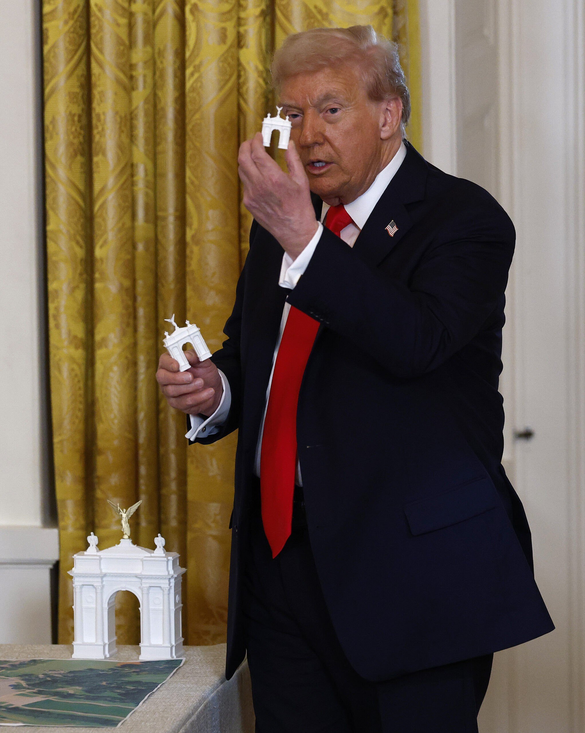 President Donald Trump holds models of an arch