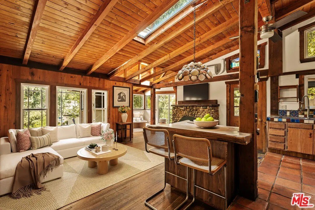 The great room is highlighted by colorful stained glass windows, a sea shell shaded hanging lamp, a live edge wood slab island bar.