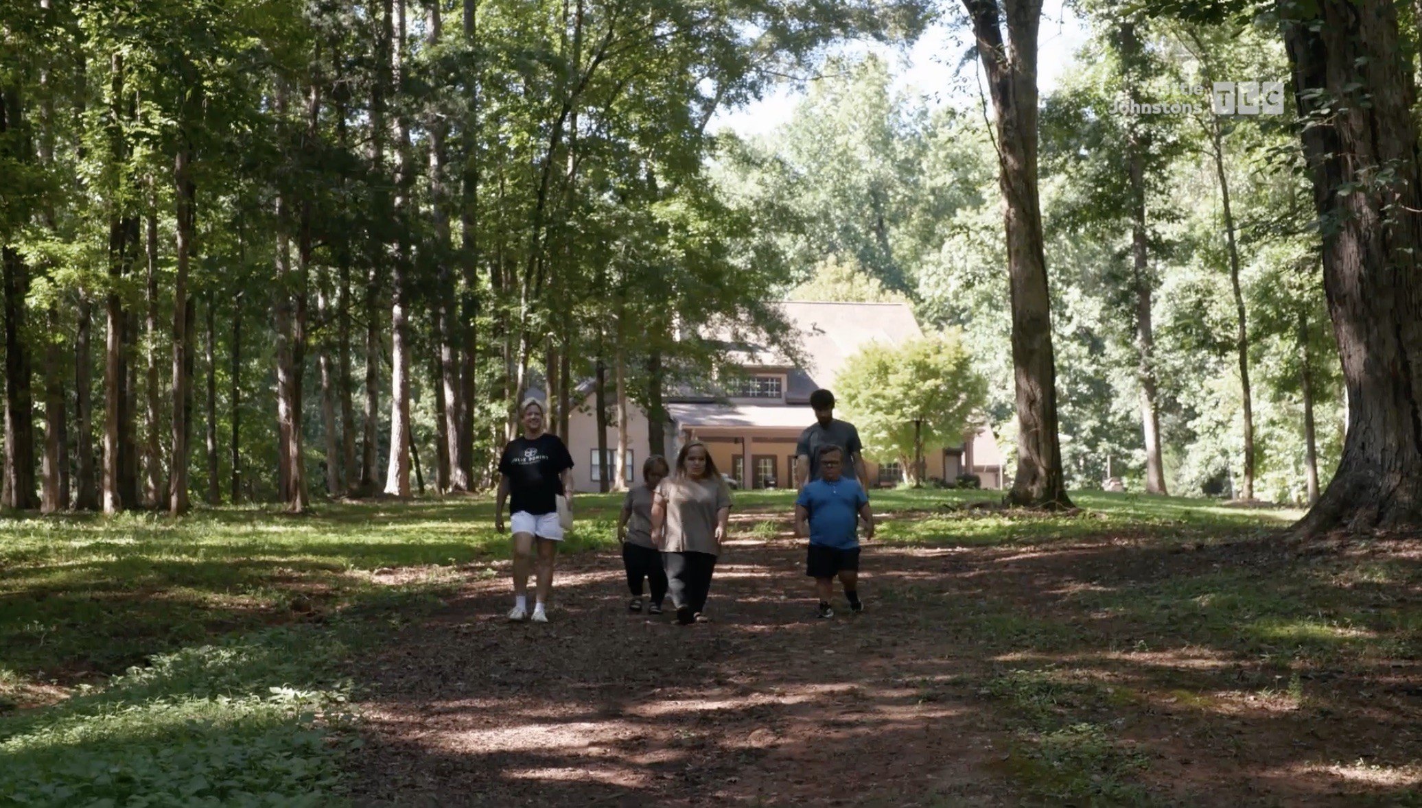 Liz and Brice's wedding site is located down a dirt path that is shaded by a grove of mature trees with a bed of green sprouts at the base.