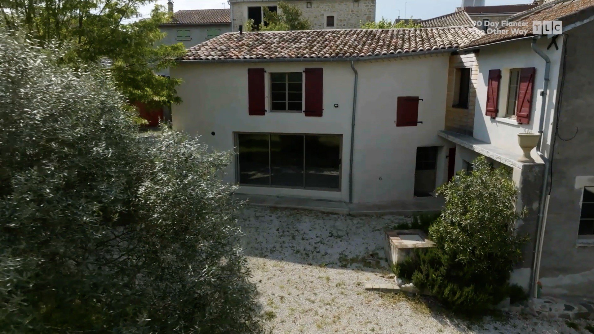 The Berryman family's new home is a two-story cream dwelling featuring oxblood-colored shutters that flank the exterior windows.