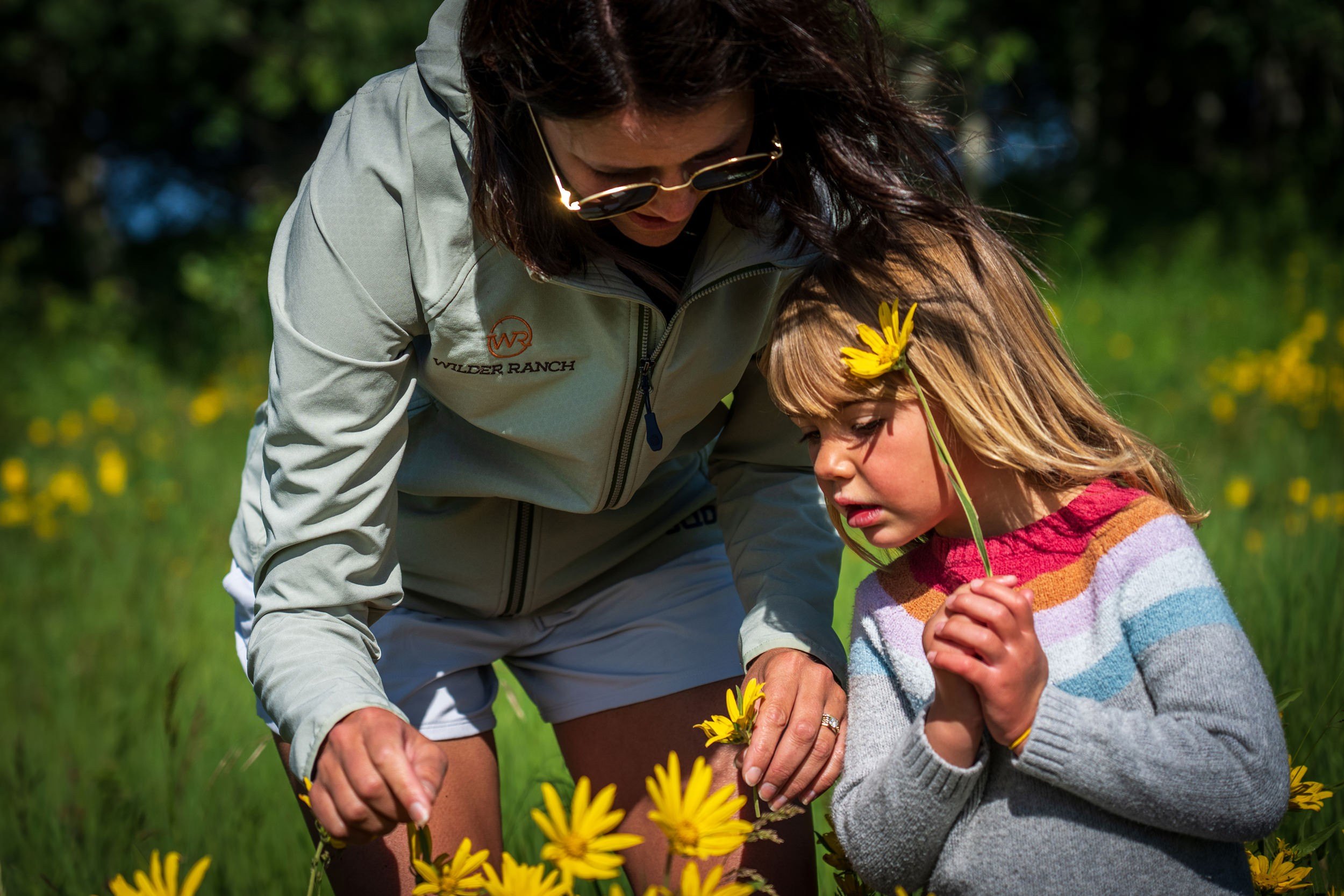 A woman and a young girl are admiring yellow flowers
