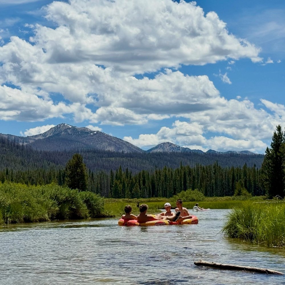 Friends Floating on Inflatable Tubes Down a Scenic Mountain River