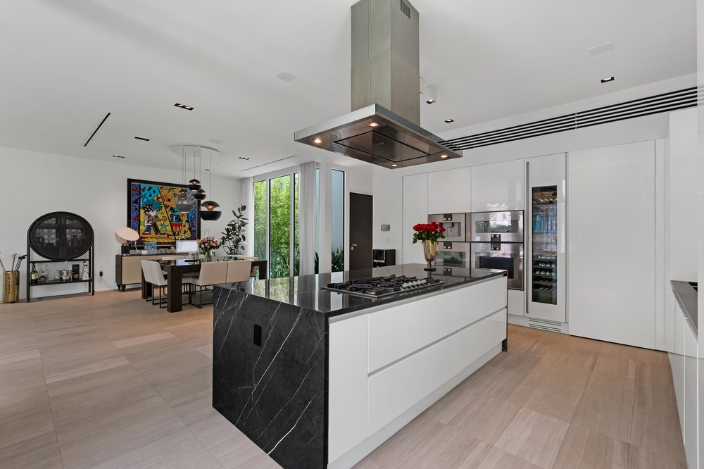 A high-end kitchen featuring a large black marble island with a built-in stovetop and professional-grade stainless steel appliances.