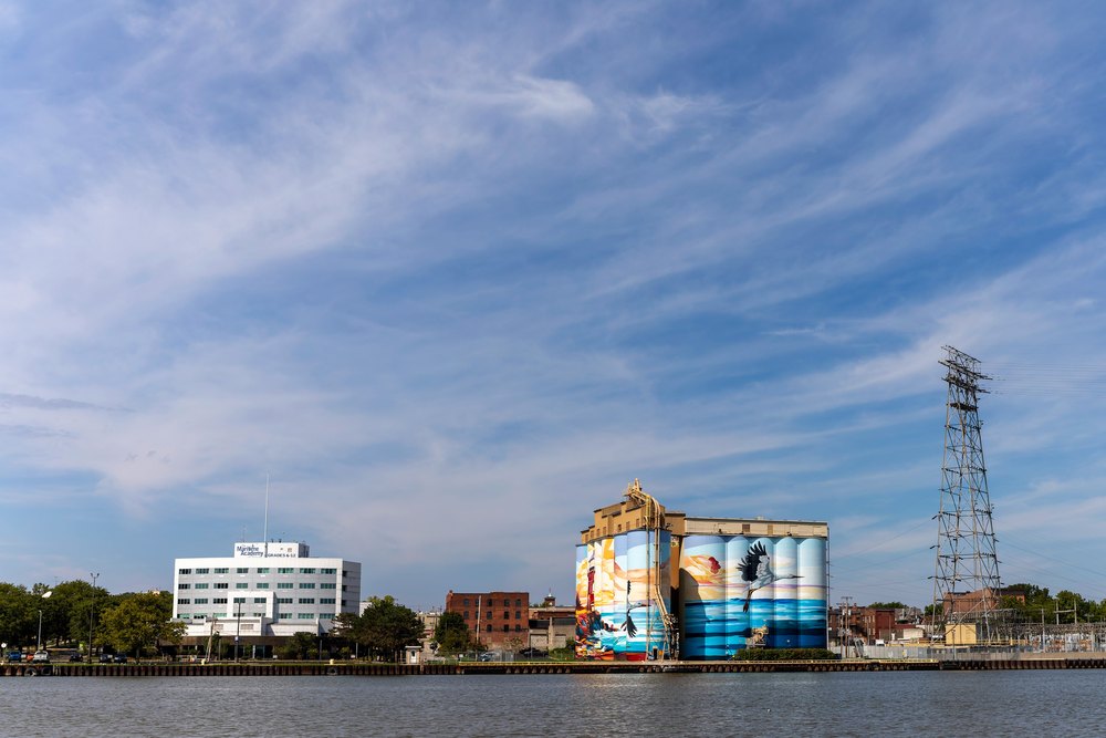 Toledo, Ohio USA September 9 2026: Industrial waterfront along the Maumee River in Toledo, Ohio, with grain silos, utility structures and downtown buildings.
