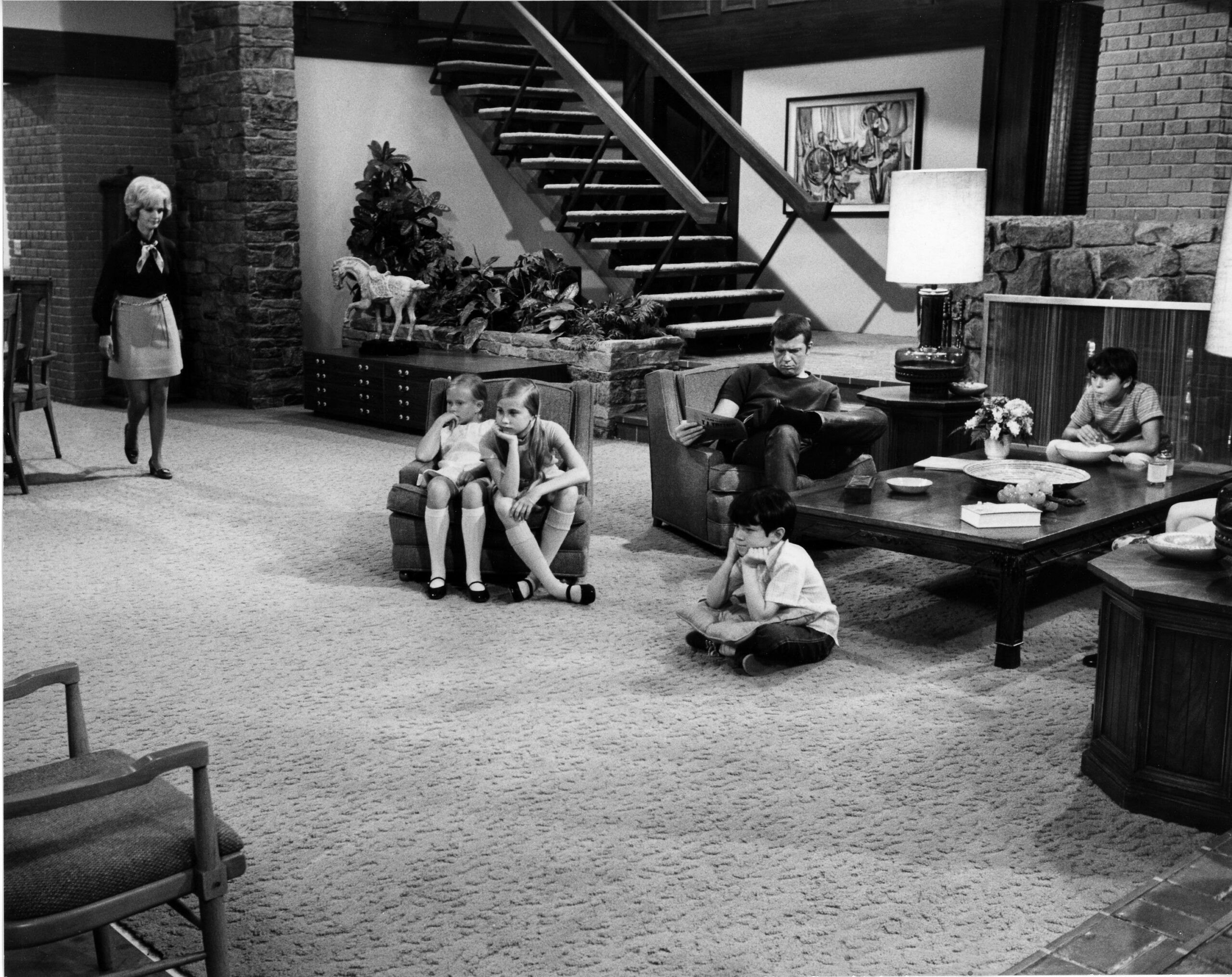 A photo of the cast of The Brady Bunch during filming showing the interior of their home