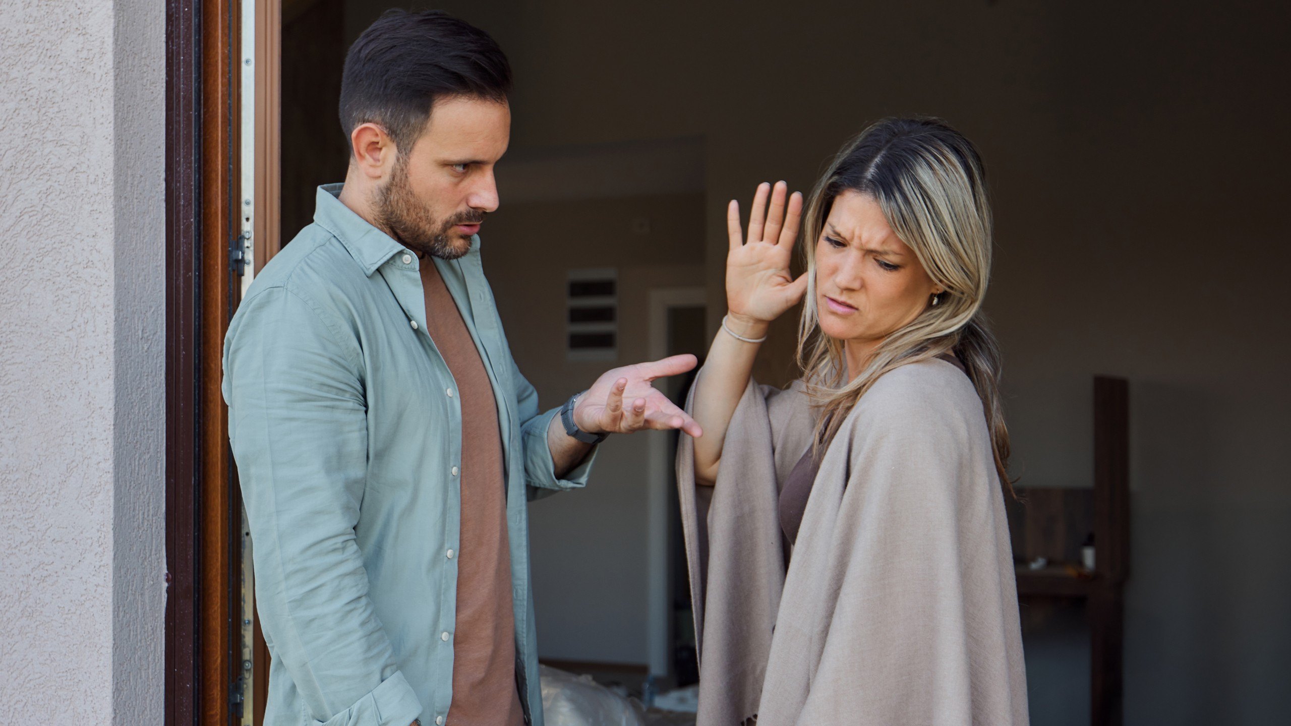 Two people emphatically arguing at their home