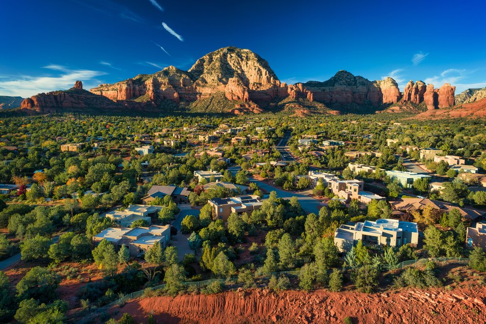 Aerial view of suburban sedona arizona residential buildings lush greenery red rock mountains