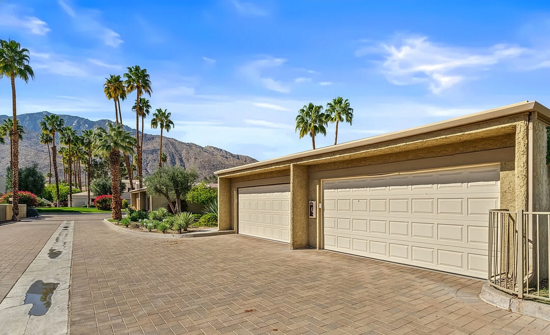 Attached two-car garages on a paved driveway with palm trees
