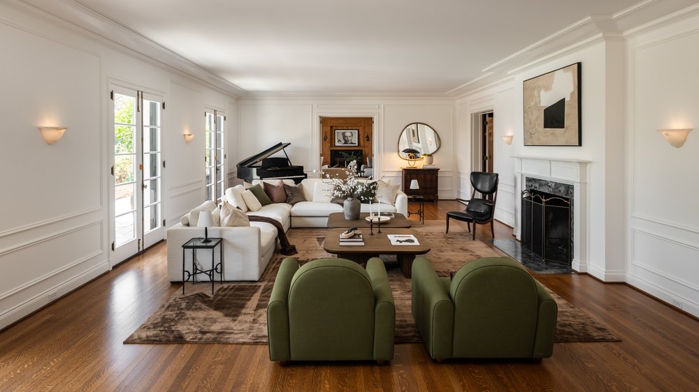 Bright and spacious living room with hardwood floors, a large white sectional sofa, and a fireplace.