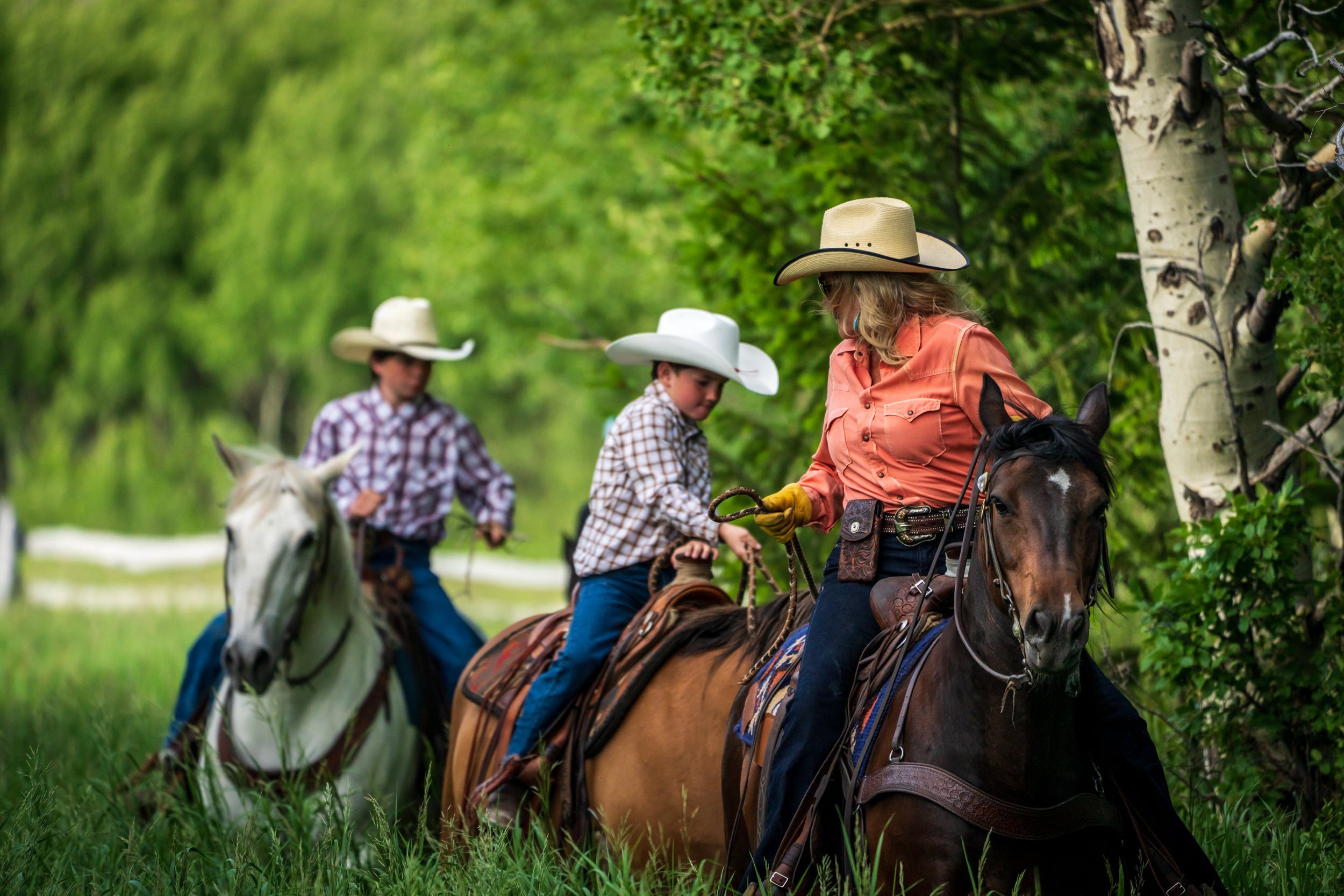 Three people in cowboy hats riding horses