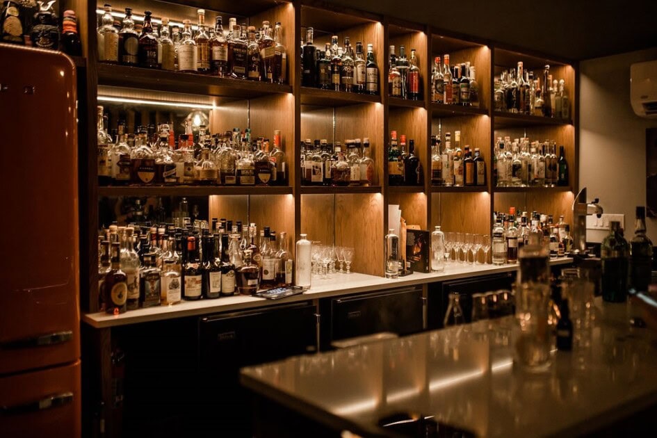 liquor bottles sit on dimly lit shelves at The Doctor's Office's back bar in Seattle