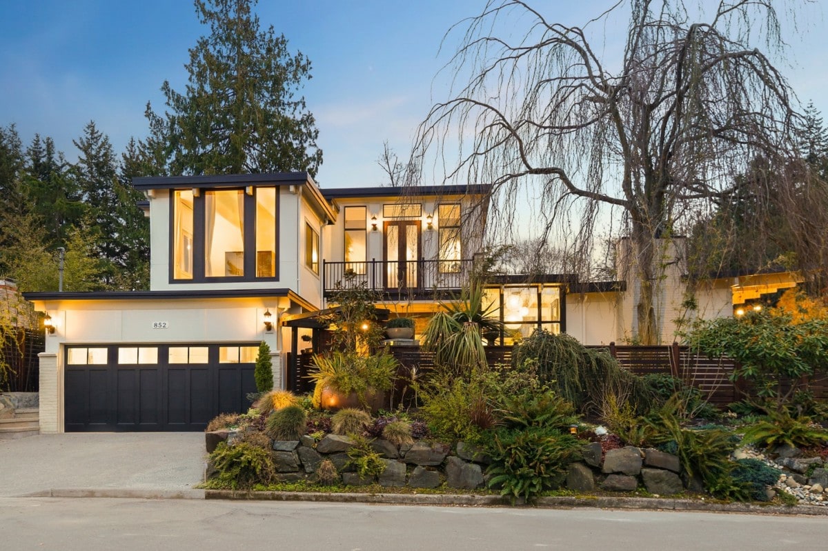 A two story white contemporary-style home with black garage and trim