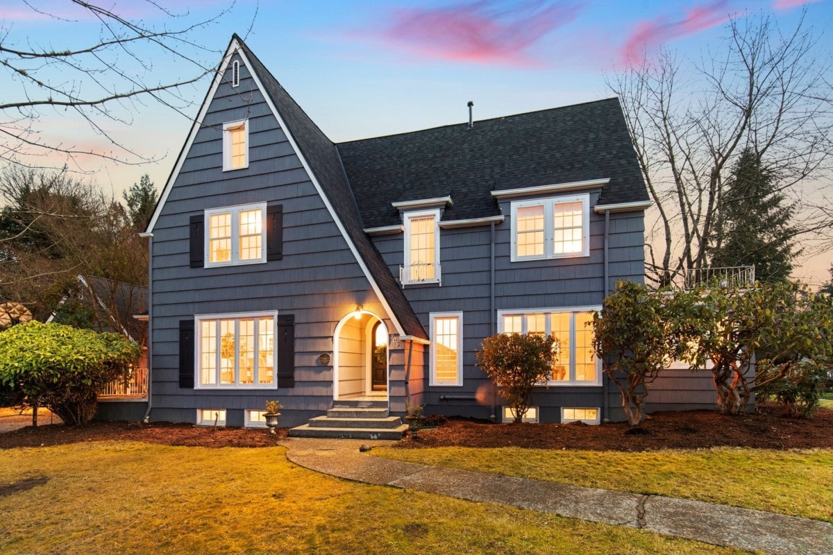 two story cottage style home painted blue with an arched doorway