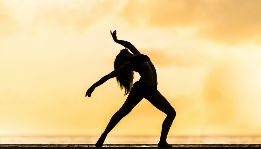 Shadow of woman dancing in front of gold backdrop