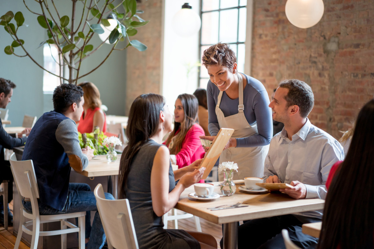 Friendly waitress serving couple at a restaurant in Germantown Getty