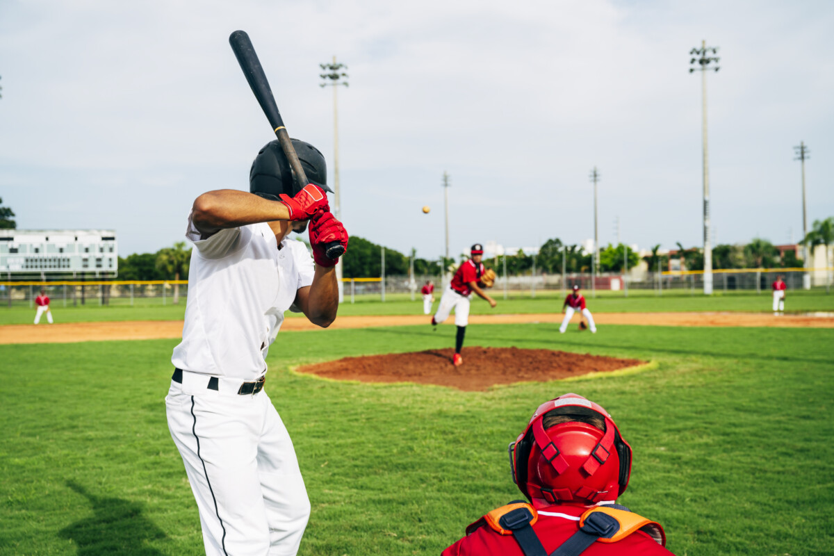 Rear view of baseball batter and catcher watching the pitch
