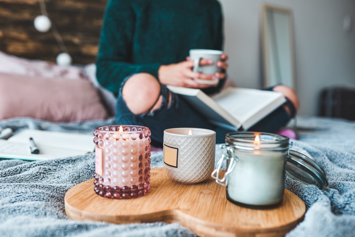 Cropped shot of an unrecognizable young woman relaxing with a book and a cup of coffee on her bed at home