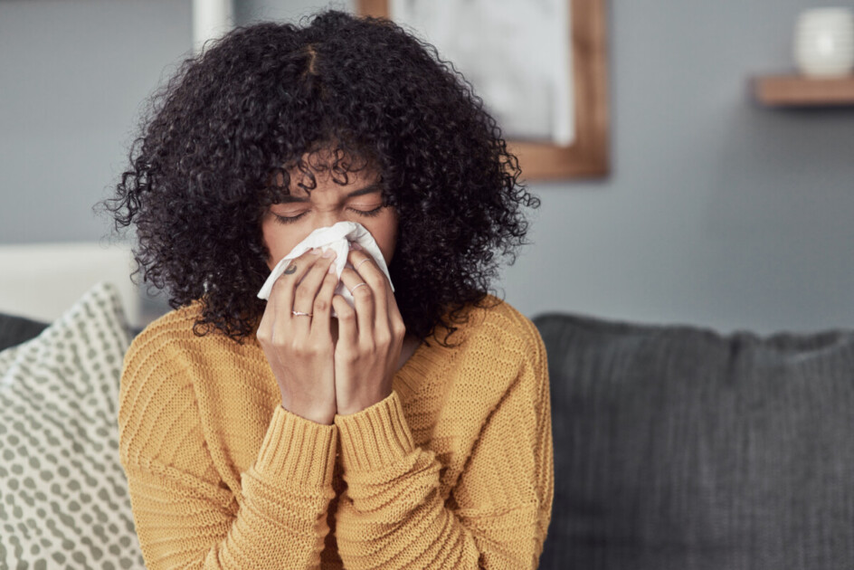 woman blowing her nose with a tissue at home