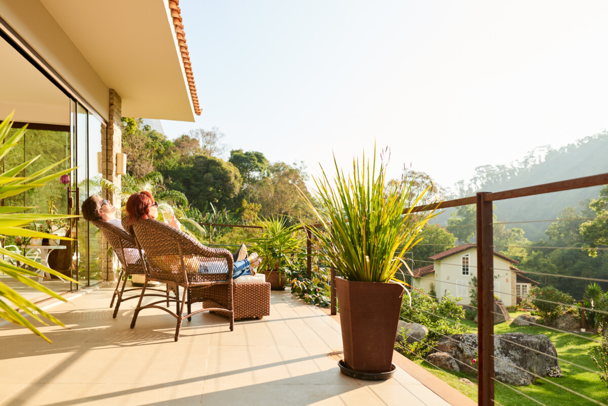 Shot of a couple relaxing in the chairs at a balcony