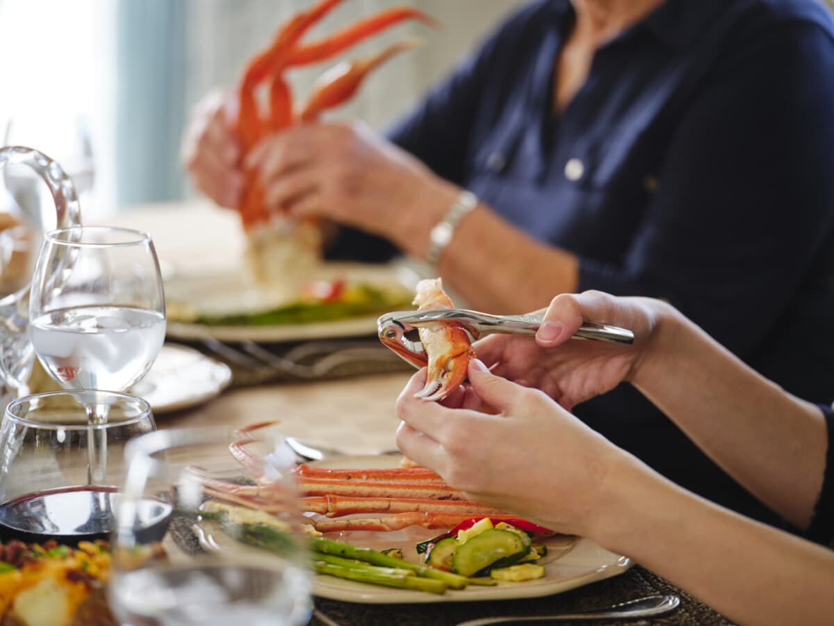 A table setting for a luxury dinner with steak, lobster, crab along with cocktails, champagne, and wine.