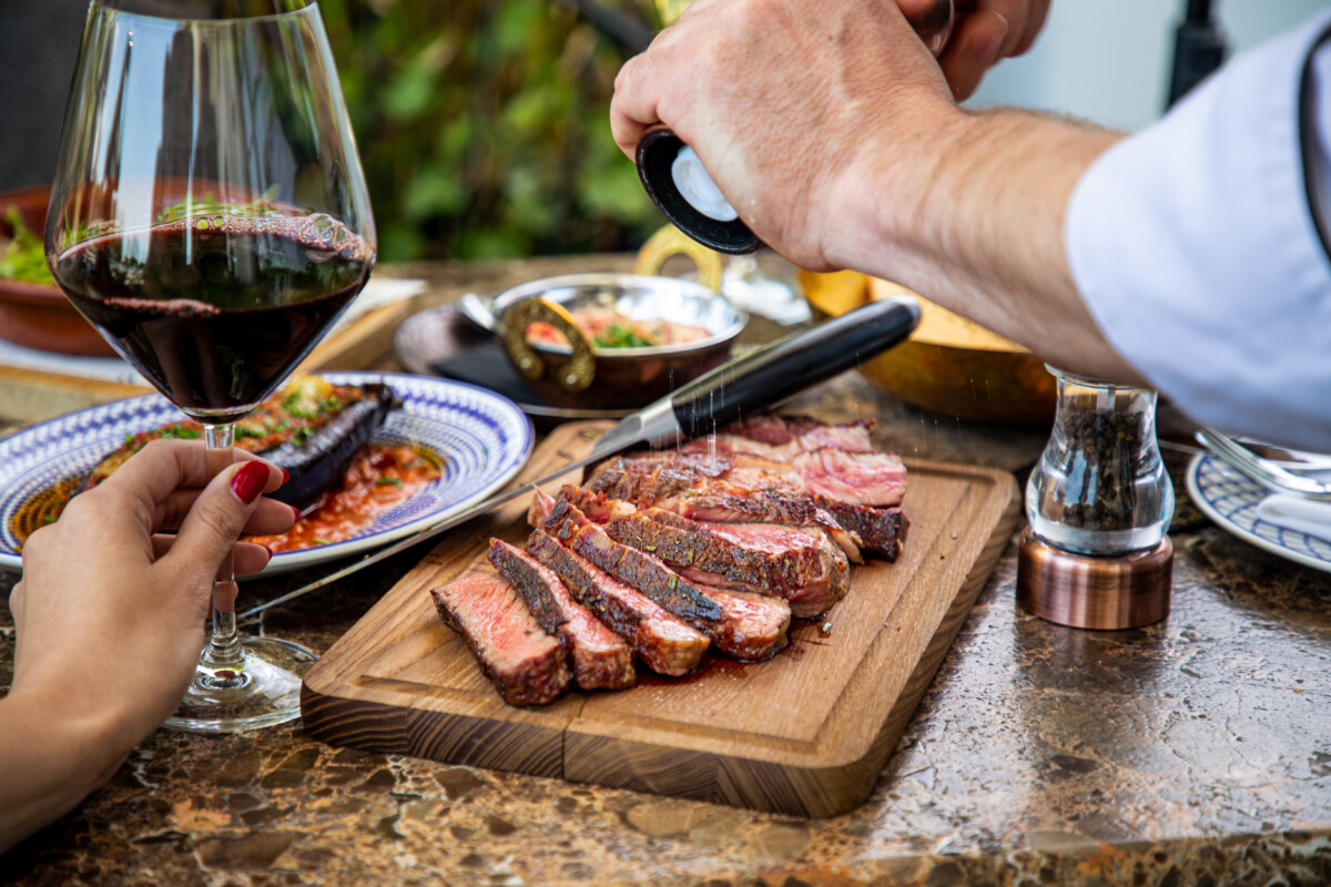 seasoning a steak over a wooden board